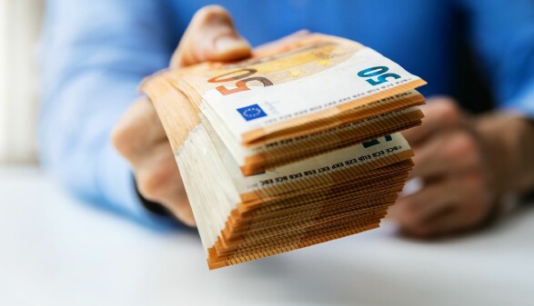 Man hält mehrere 50-Euro-Scheine in der Hand