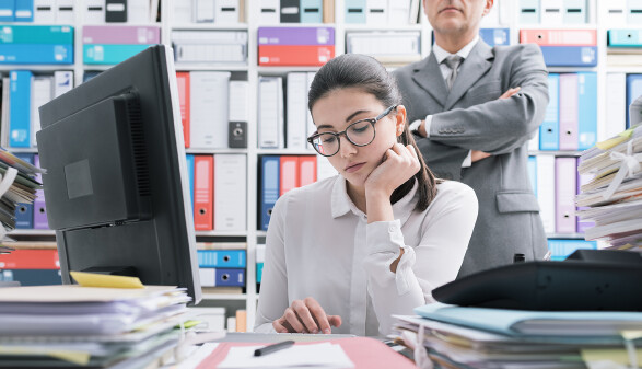 Chef beobachtet Lehrling im Büro.