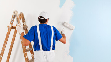 Maler steht auf einer Leiter und malt die Wand aus