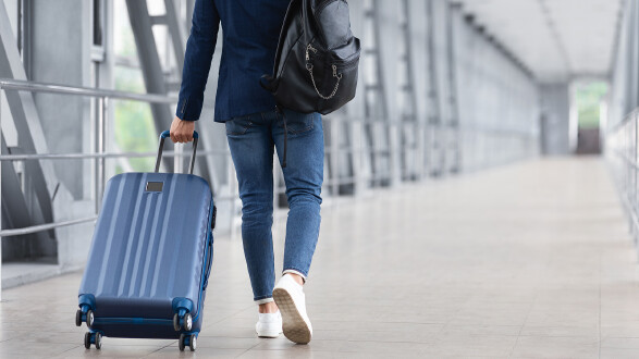 Mann mit Koffer am Flughafen auf dem Weg zum Gate
