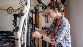 Junge Frau repariert ein Mountainbike in einer Werkstatt