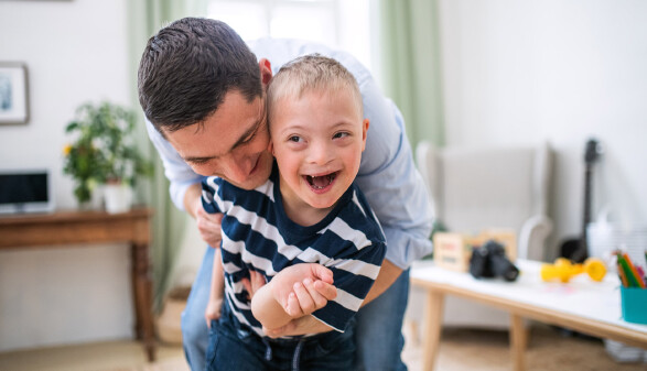 Papa spielt mit glücklichem Sohn mit Down Syndrom zu Hause