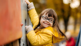 Glückliches Kind mit Down Syndrom geniest die Zeit am Spielplatz