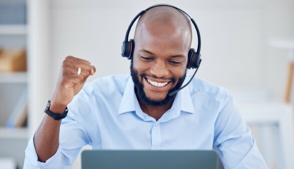 Callcenter-Agent mit Headset l&auml;chelt w&auml;hrend der Arbeit
