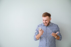 Mann schaut ver&auml;rgert auf sein Smartphone