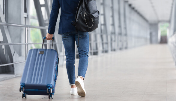 Mann mit Koffer am Flughafen auf dem Weg zum Gate