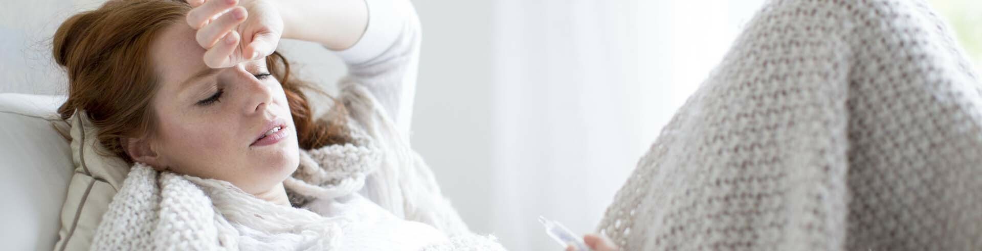 Frau liegt krank im Bett