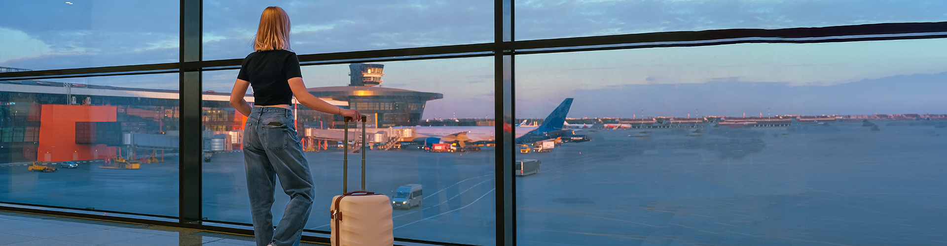 Frau steht am Flughafen und liest die Ankunftstafel