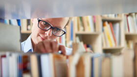 Frau in der Bibliothek sucht ein Buch zum Ausleihen