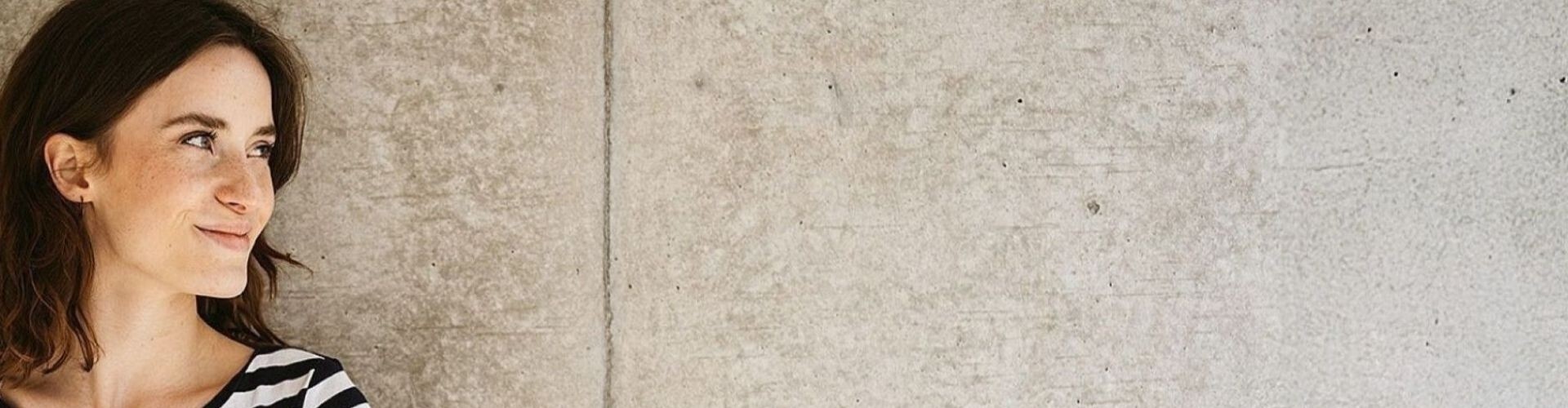 Junge Frau steht vor einer Steinmauer