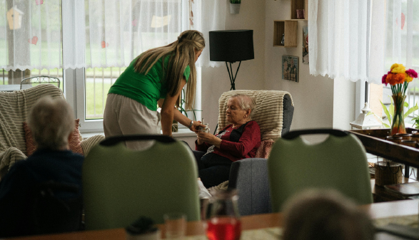 Pflegerin reicht Patientin eine Tasse