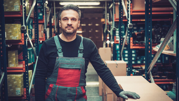 Arbeiter steht in einem Lager zwischen Regalen