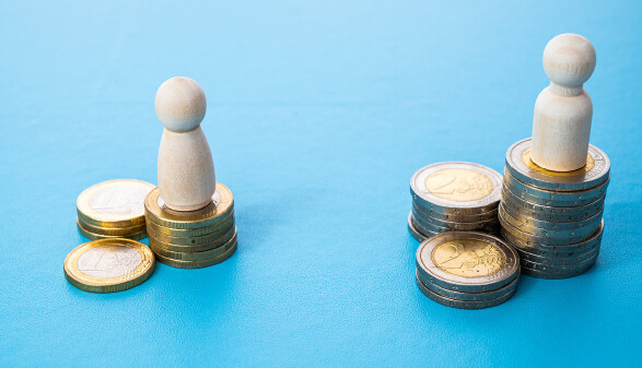 Konzept ungleicher Bezahlung am Arbeitsplatz zwischen Männern und Frauen. Holzfiguren auf Münzstapeln.