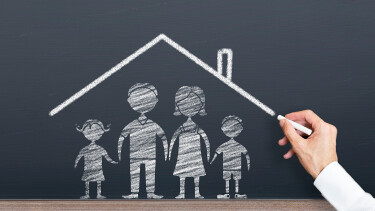 Mann zeichnet ein Dach und darunter eine Familie