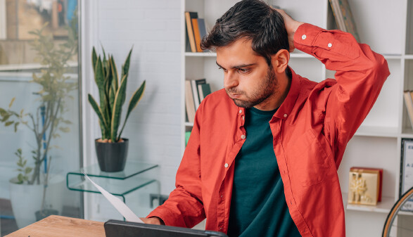 Gestresster junger Mann schaut auf ein Dokument