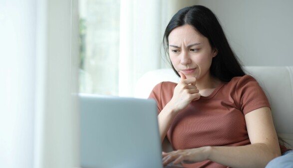 Frau schaut skeptisch auf ihren Laptop
